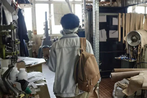 Mujer entrando a un taller de mochilas personalizadas en donde se ven materiales.
