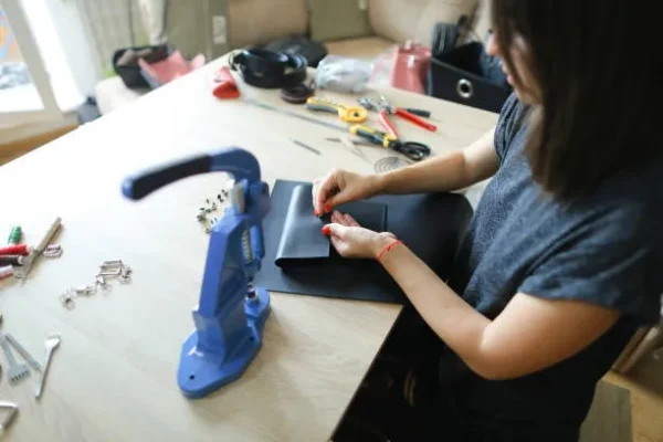Mujer utilizando una máquina de coser para realizar la personalización de mochilas en un taller.